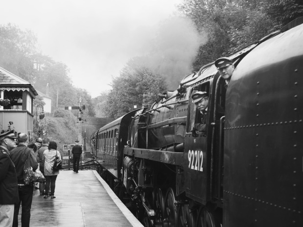 A steam train, with the crew leaning out, in black and white