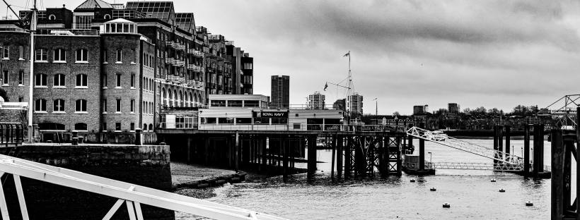 A black and white photo of London's south bank, with part of the river and a couple of industrial looking docks